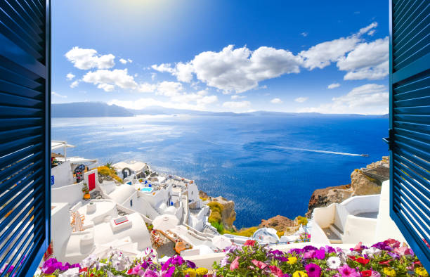 widok przez otwarte okno z okiennicami bielonej wioski oia wznoszącej się nad błękitnym morzem egejskim i kalderą na wyspie santorini w grecji. - fira zdjęcia i obrazy z banku zdjęć