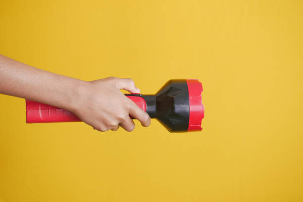 istock hand holding a tourch light against yellow background, 1382396387