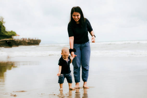 istock asian young woman watching her son when walking on the beach 1382397525