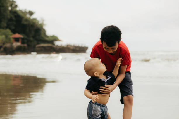 istock a kid teaching his young brother walking on the beach 1382397641