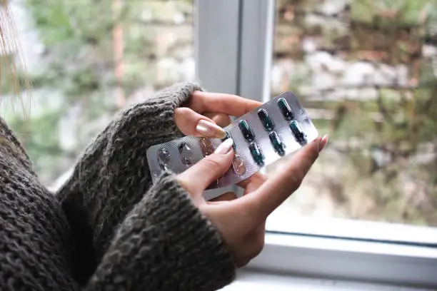 Photo of Blonde Young adult woman with acne holding Acne pills