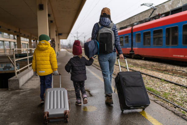 mère célibataire et deux jeunes enfants à la gare - winter migration photos et images de collection