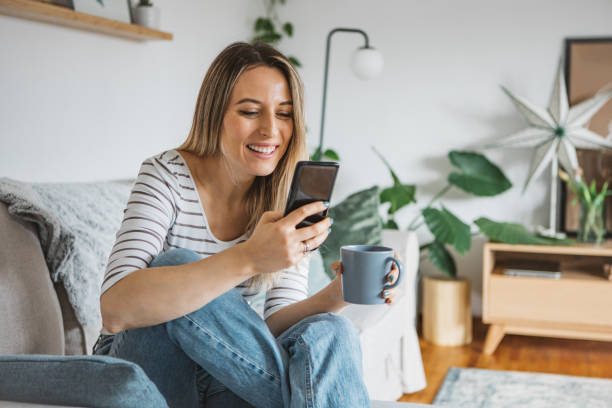 istock Young woman using cell phone on a couch at home 1382402988