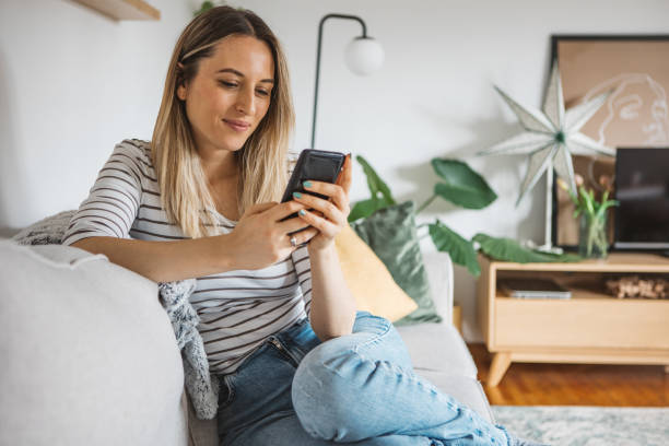 istock Young woman using cell phone on a couch at home 1382403030