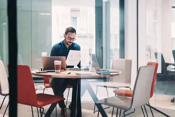 Photo of Businessman working alone in a glass office