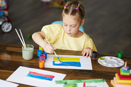 Girl draws a picture of the war in Ukraine. Bright drawing with colors of the State flag of Ukraine, yellow and blue.