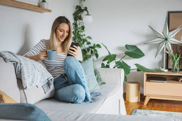 istock Young woman using cell phone on a couch at home 1382410814