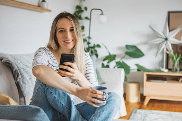 istock Young woman using cell phone on a couch at home 1382411383