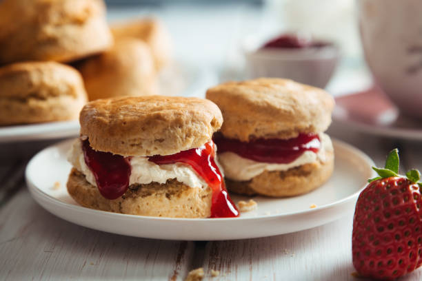 Delicious scones with clotted cream and strawberry jam for tea time Traditional british scones with clotted cream and strawberry jam for tea time scone photos stock pictures, royalty-free photos & images