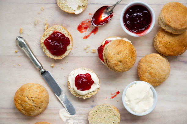 Delicious british scones with strawberry jam and clotted cream Top view of traditional british scones with clotted cream and strawberry jam for tea time on a wooden table scone photos stock pictures, royalty-free photos & images