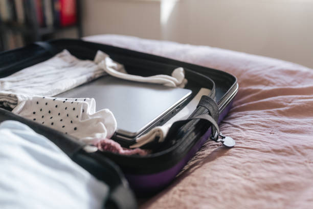 istock Purple suitcase with clothes and a laptop 1382428322