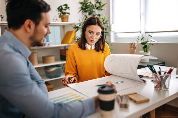 Professionals discussing blueprints on desk in small office stock photo