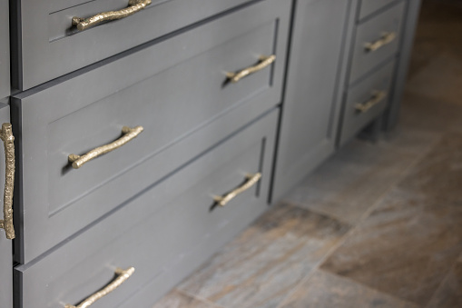 Gray kitchen cabinets with modern gold drawer pulls in a recently renovated kitchen with tile floors.
