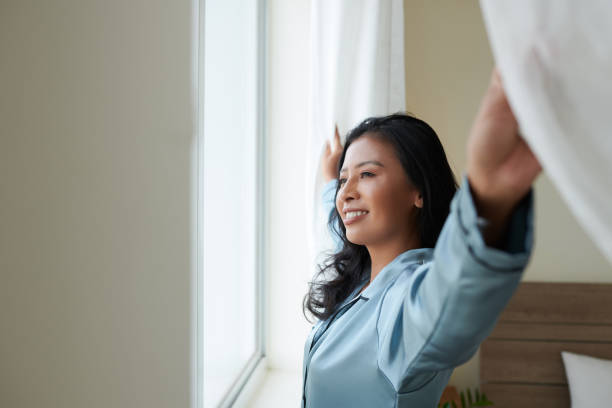 istock Young Woman Opening Curtains 1382449405