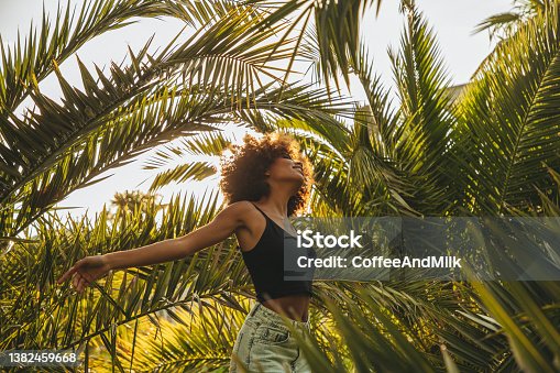 istock Pretty young afro woman among palm trees 1382459668