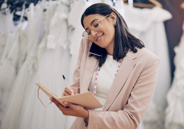 istock Shot of an attractive young seamstress writing notes while talking on her cellphone 1382460366