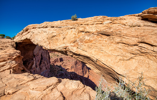 Panoramic view at iconic Mesa Arch under a blue summer sky in Canyonlands National Park, Utah