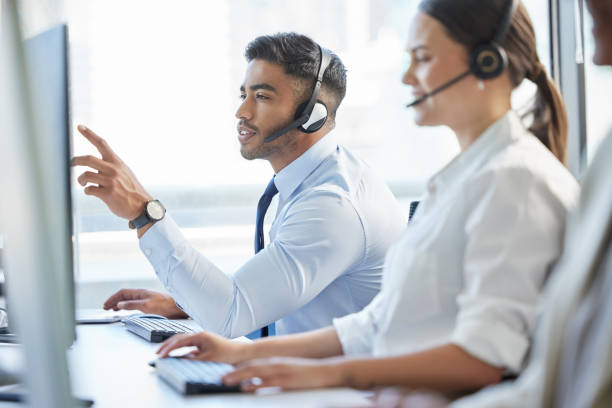 istock Shot of a man pointing at his computer while wearing a headset in a call center 1382470997