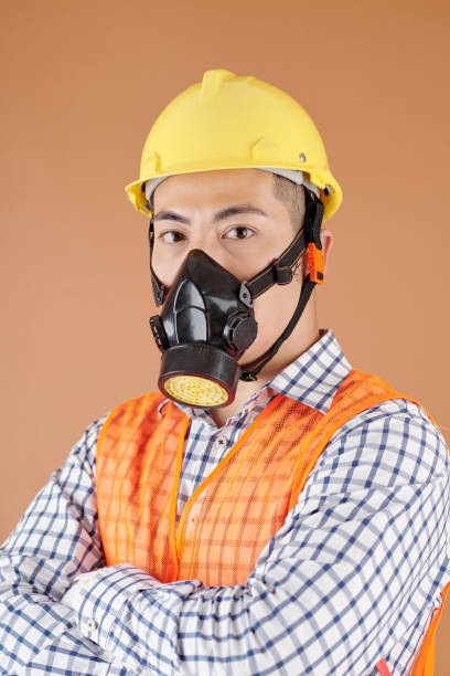 Respirator type half mask with replaceable filters on yellow background. A special means of personal respiratory protection against the ingress of aerosols or harmful gases. Selective focus.