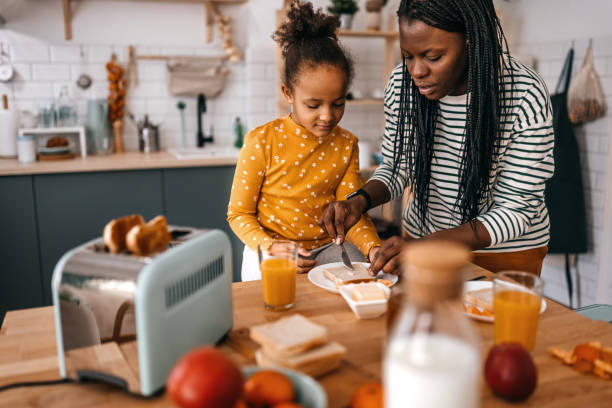 madre e figlia che fanno colazione sul tavolo da pranzo in cucina - tostapane foto e immagini stock