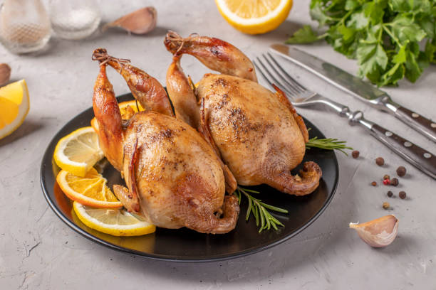 istock Baked quails with lemon and orange served on a dark plate on a gray background 1382494913