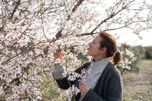 Profile of a woman smelling almond flowers in spring