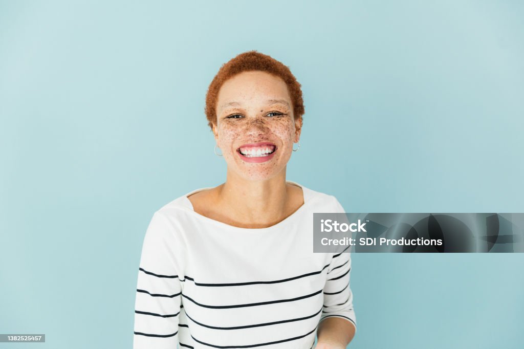Woman in striped shirt The woman in the striped shirt against blue background with a toothy smile. Portrait Stock Photo