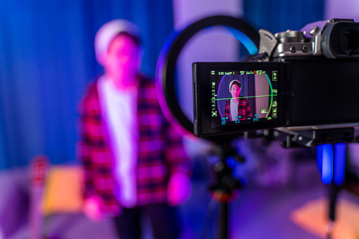 teenage  boy filming videos at home and talking to camera set on ring light, young blogger concept, copy space