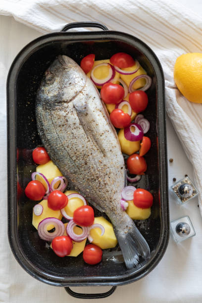 istock Dorade Fish with potatoes and vegetables prepared in a casserole dish for grilling 1382530978