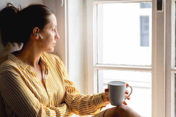istock Young woman sitting and looking through window 1382535030