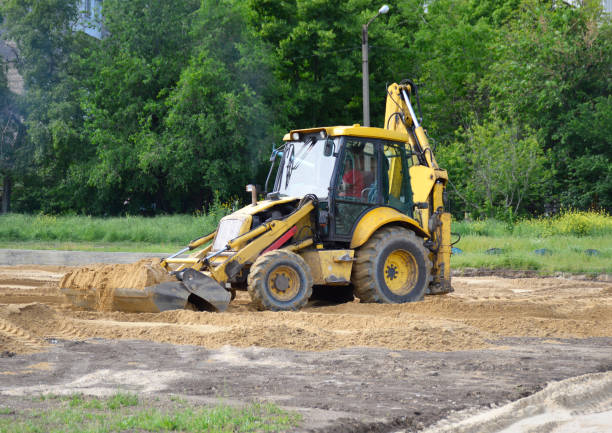 A backhoe pushing a pile of sand.This is a type of excavating equipment consisting of a tractor-like unit fitted with a loader-style shovel-bucket on the front and a backhoe on the back