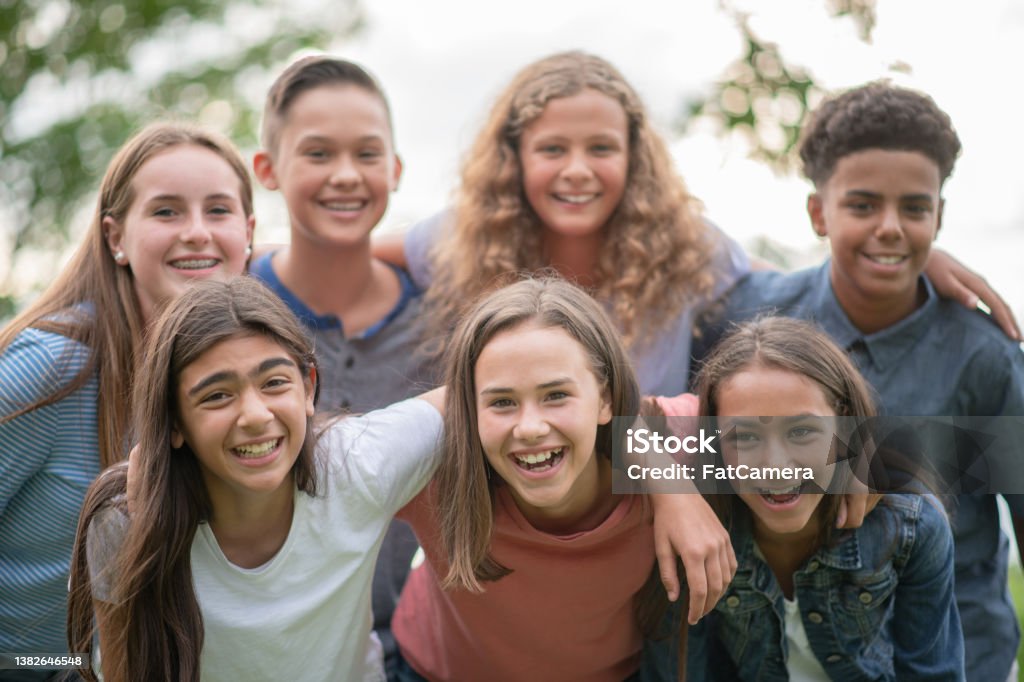 Elementary Students Outdoor Portrait A large group of Elementary students huddle together closely outside as they pose for a portrait.  They are each dressed casually and are smiling as they enjoy time outside together. Teenager Stock Photo