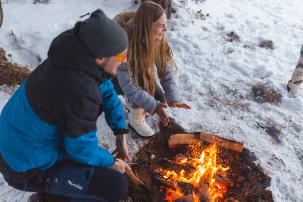 istock Two young friends sitting beside a campfire while camping outdoors in the winter 1382649620