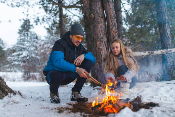 istock Two young friends sitting beside a campfire while camping outdoors in the winter 1382649623