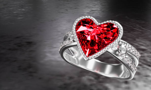 The large red diamond heart shape is surrounded by many diamonds on the ring made of platinum gold placed on a gray background. Elegant wedding diamond ring for women.  3d rendering stock photo