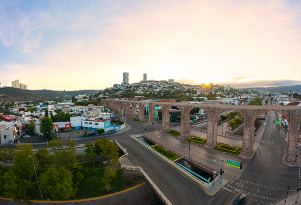 vue panoramique aérienne sur le célèbre aqueduc de querétaro dans le centre de la ville entouré de bâtiments avec un beau lever de soleil en arrière-plan - queretaro city photos et images de collection