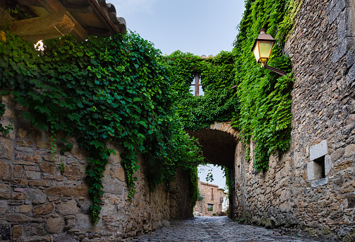 View of a flowered street in the medieval village of Peratallada, in Girona, Catalonia, Spain.\