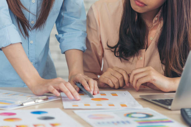 istock Two asian Female freelance reading financial graph charts Planning analyzing marketing data. Asian people team working office firm. Two businesswomen team meeting using laptop at company office desk. 1382662065
