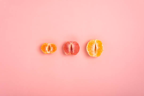 みかん、グレープフルーツ、オレンジは、膣と女性の生殖能力の�象徴として桃の背景に半分にカット - vagina ストックフォトと画像