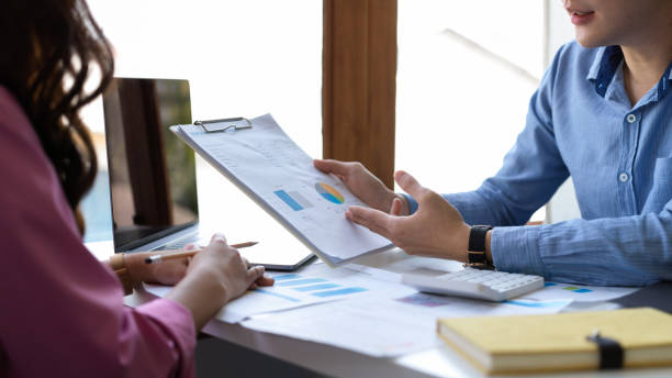 istock Male financial advisor explains data report to female client. 1382701438
