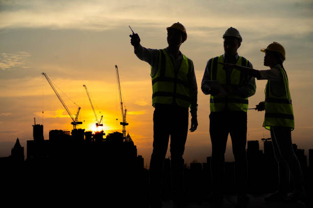 istock Silhouette of Team engineer at construction site. Successful architect wearing helmet with copy space. Business, Building, Teamwork and People Concept. Construction Business Team at Construction Site. 1382733855