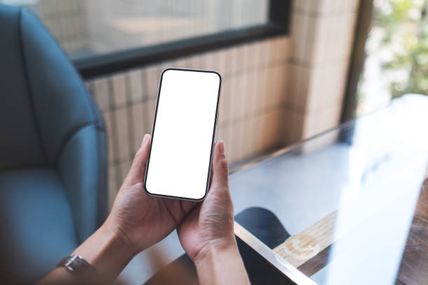 Mockup image of a woman holding and using mobile phone with blank desktop screen stock photo