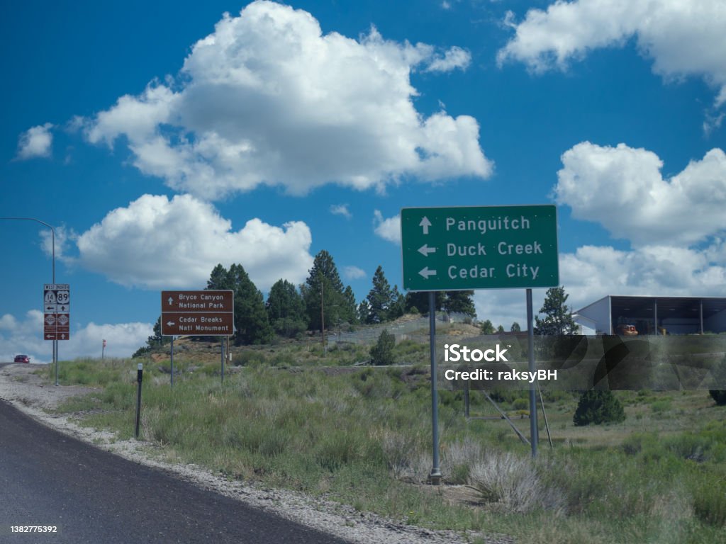 Roadside sign with directions to Bryce Canyon National Park, Panguitch, Duck Creek and Cedar City in Utah. Agricultural Field Stock Photo