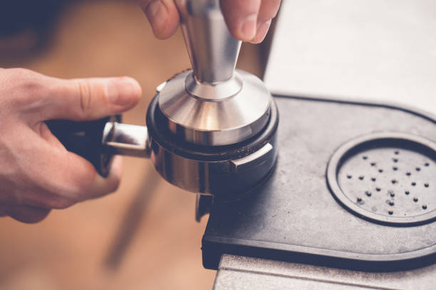 barista manomissione caffè in portafiltro usando tamper. processo di preparazione del caffè fresco ravvicinato - tampering foto e immagini stock