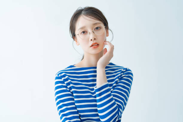 A young woman with glasses and a serious expression A young woman with glasses and a serious expression indoors japanese ethnicity stock pictures, royalty-free photos & images