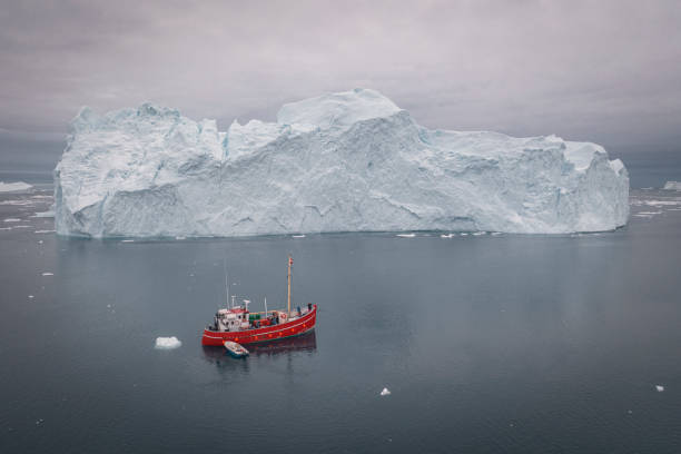 istock SMALL BOAT SAILING BETWEEN BIG ICEBERGS FROM AERIAL VIEW 1382808975