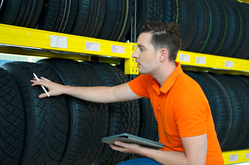 Employee is checking tires at car service station. Car service station and small business concept.