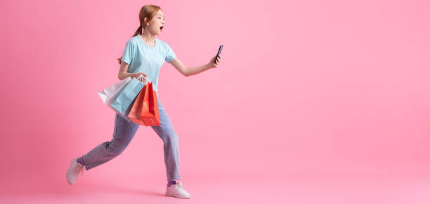 joven asiática sosteniendo bolsa de compras sobre fondo rosa - freedom on the phone urgency telephone fotografías e imágenes de stock