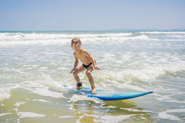 istock Healthy young boy learning to surf in the sea or ocean 1382814111