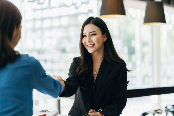 Two Businesswomen Shaking Hands In Modern Office